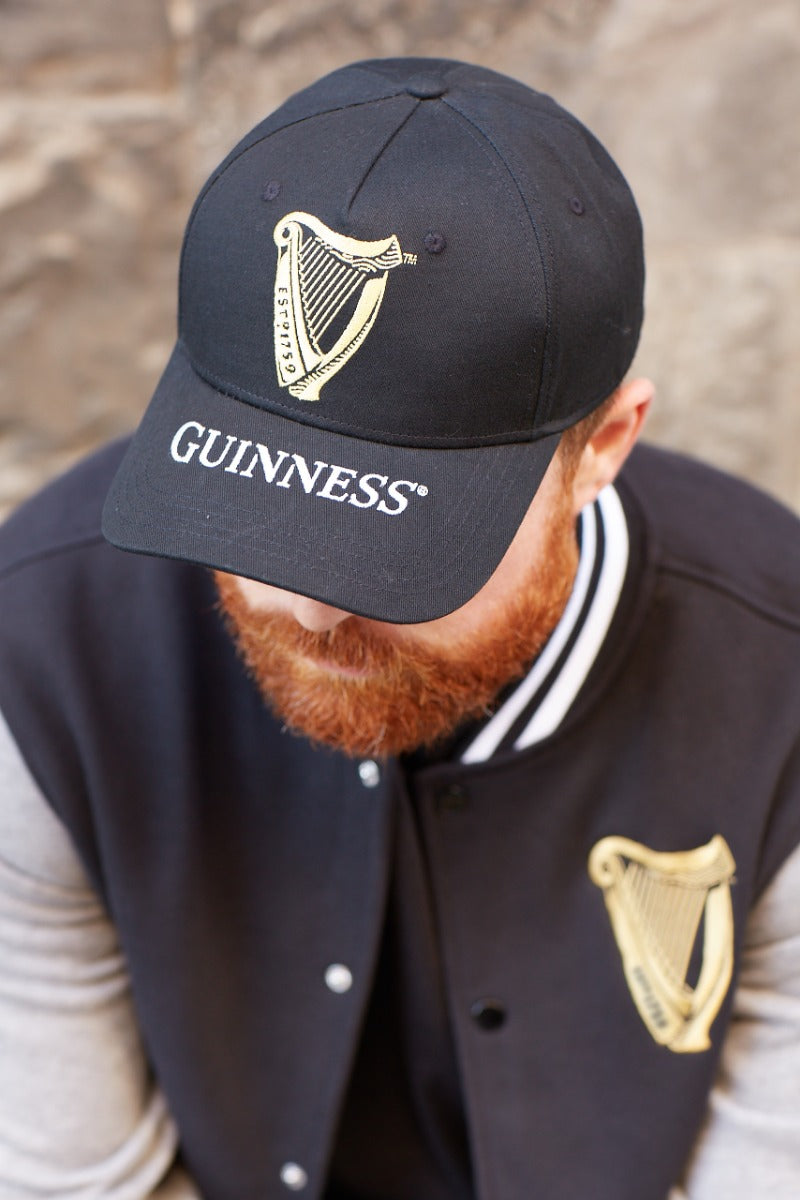 A man with a beard wearing a Guinness Harp Baseball Cap hat.
