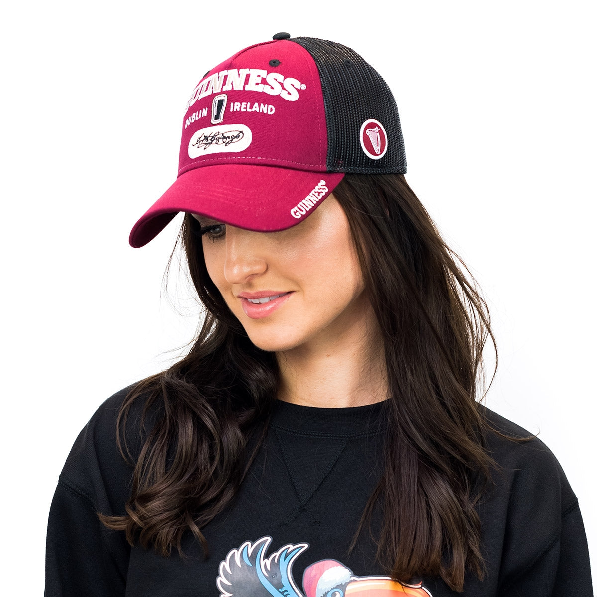 A woman wearing a Guinness Signature Burgundy Trucker Mesh Baseball Cap Adjustable.