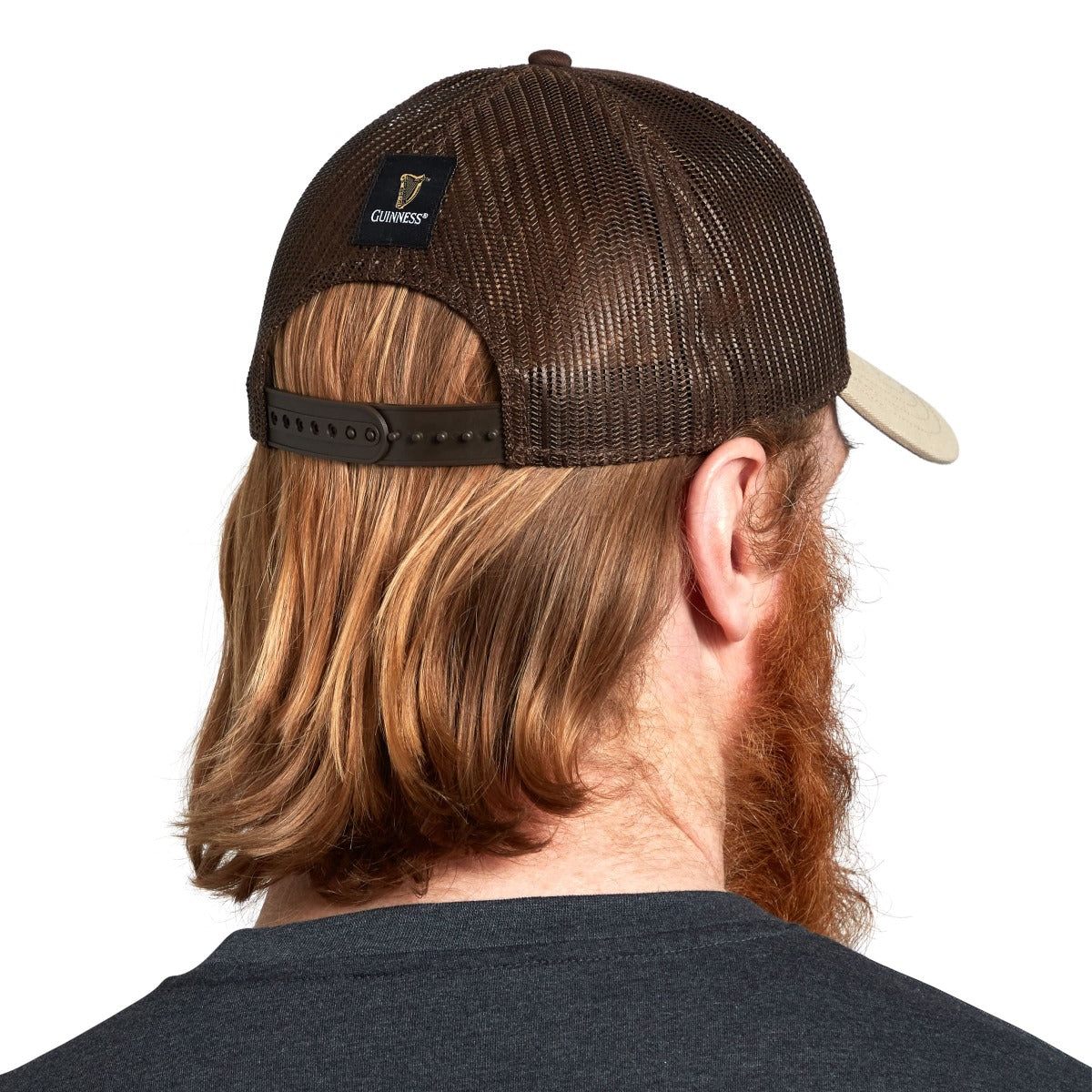 The back view of a man wearing a Guinness Trucker Premium Brown with Embroidered Patch Cap with a red beard.