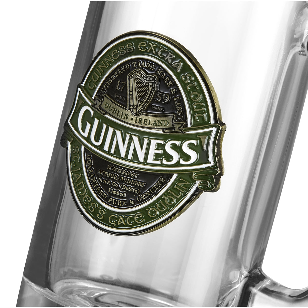 A close-up image of a clear glass featuring a Guinness logo prominently displayed on the Guinness Ireland Tankard label with gold and green accents. Text on the label includes "Guinness," "Dublin, Ireland," and "St. James’s Gate Dublin.