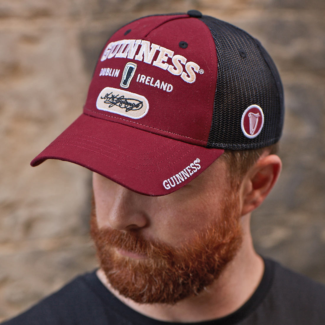 An adjustable man with a beard wearing a Guinness Signature Burgundy Trucker Mesh Baseball Cap Adjustable.