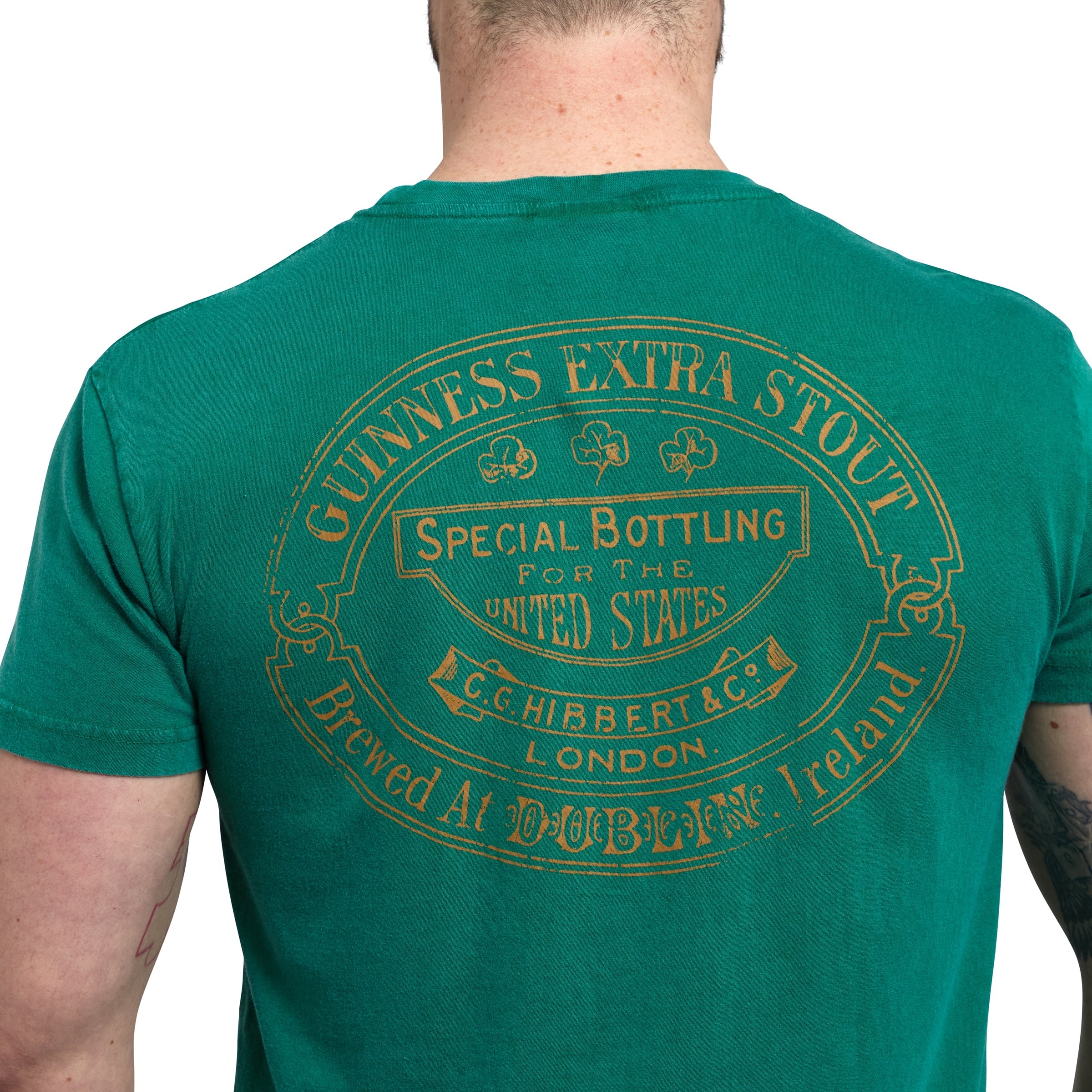 A Guinness lover wearing a Green Guinness Harp Premium Tee from the Guinness Webstore US, featuring text about special bottling for the United States by C.G. Hibbert & Co. London.